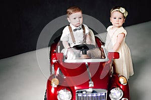 Two babies wedding - boy and girl dressed as bride and groom playing with toy car