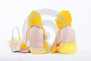 Two babies in chicken costumes with white basket from behind