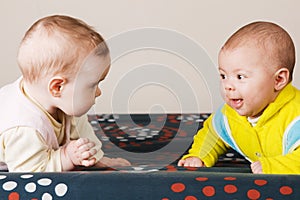 Two babies crawling on a sofa