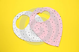 Two baby bibs on yellow background, top view. First food