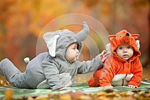 Two baby boys dressed in animal costumes in park