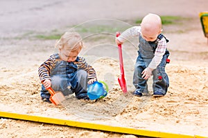 Two baby boys playing with sand