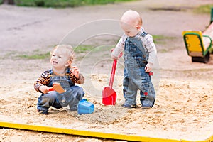 Two baby boys playing with sand