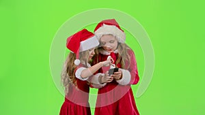 Two baby girls look at the pictures on the phone and laugh. Green screen