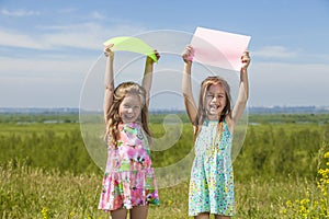 Two baby girls in summer dresses on the nature of holding the co