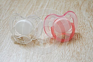 Two baby nipples. pacifiers pink and white.