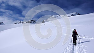 Two backcountry skiers on a tour in the Austrian Alps and putting in new tracks on their way to the summit