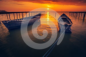 Two backlit fishing boats with the sun in the background at sunrise or sunset