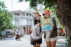 two backpacker girls looking at a map while searching for destinations