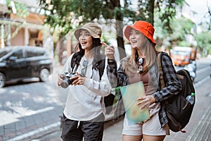 two backpacker girls with pointing fingers looking for tourist destinations