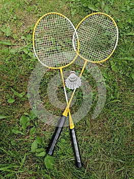 two badminton reckets with shuttlecorck on green grass from above