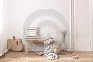 Two bags made of straw next to wooden table with striped pillow