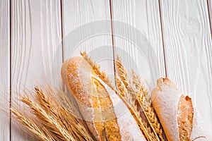Two baguettes ears of wheat on white painted