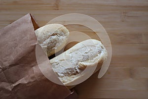 Two baguettes in a paper bag lie on a wooden board. selectiv focus