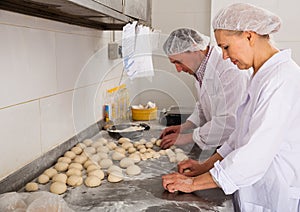 Two bakers portioning and shaping dough