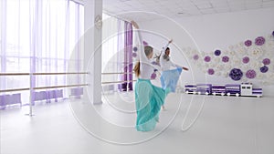Two ballerinas is rehearsing a dancing elements together.