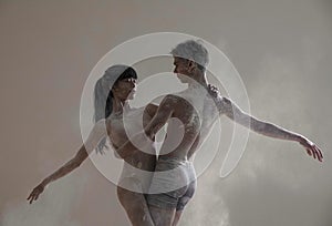 Two ballet dancers dance against white flour cloud in air