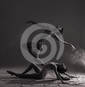 Two ballet dancers perform dance against background of white flour cloud in air