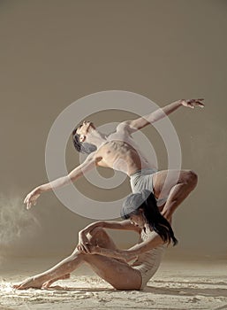 Two ballet dancers perform dance against background of white flour cloud in air