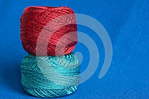 Two balls of a brilliant yarn on a blue background