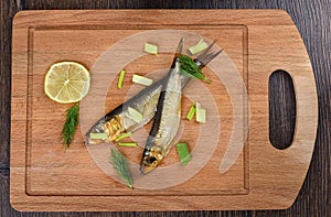 Two baltic herrings cold smoked with dill, green onions and lime on a wooden cutting board