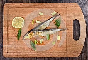 Two baltic herrings cold smoked with dill, green onions and lime on a wooden cutting board