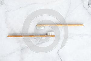 Two bamboo toothbrushes on marble background.