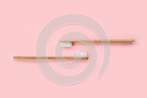 Two bamboo toothbrushes on pink background. Dental and healthcare concept.