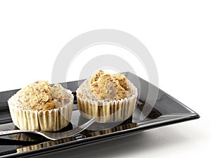 Two banana cupcake with silver fork on black rectangle dish isolated on white background