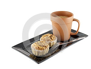 Two banana cupcakes with silver fork and cappuccino coffee in baked clay cup on black dish isolated on white background