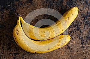 Two bananas on abstract wooden background. Top view