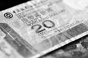 Two banknotes of twenty Hong Kong dollars on a dark background. Black and white