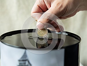 Two banks of a piggy bank, with a different amount of money and a place for text, stand on a wooden bookshelf. Female hand adds