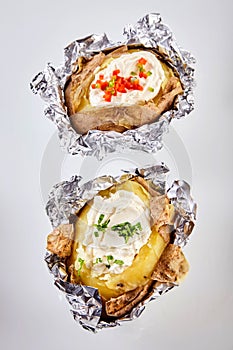 Two barbecued baked potatoes in tin foil