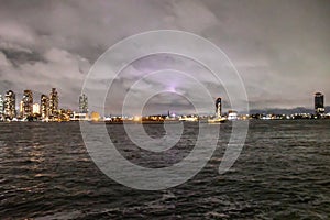 Two barges heading up the East River at night with the Queens Skyline in the background