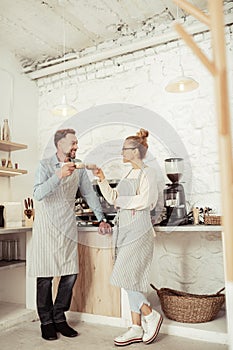 Two baristas wearing aprons drinking coffee together.