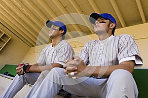 Two baseball team-mates sitting in dugout