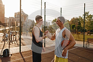 Two basketball players shake hands, outdoor court