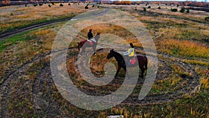 Two bay horses with equestrians are going in circle on the field