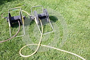 Two bay hose reel carts at green grass background of summer backyard. equipment for gardening. copy space