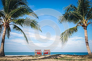 Two Beach Chairs between palm trees at the beach during a summer vacation
