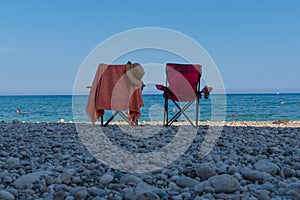 Two beach chairs by the sea. Back rear view of chairs and sea and sky in background