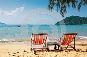 Two beach chairs on tropical beach.