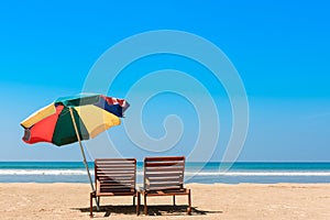 Two beach chairs and umbrella on empty tropical ocean beach