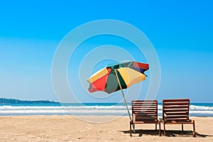 Two beach chairs and umbrella on tropical ocean beach