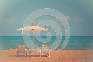 Two beach chairs and white umbrella on the tropical beach