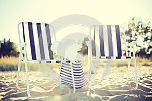 Two beach lounges with beach bag and white hat