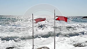 Two beach warning red flags splashing on wind.