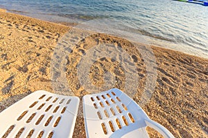 Two beachchairs on the sand near sea, closeup