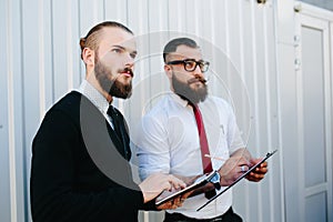 Two bearded businessman looking at something